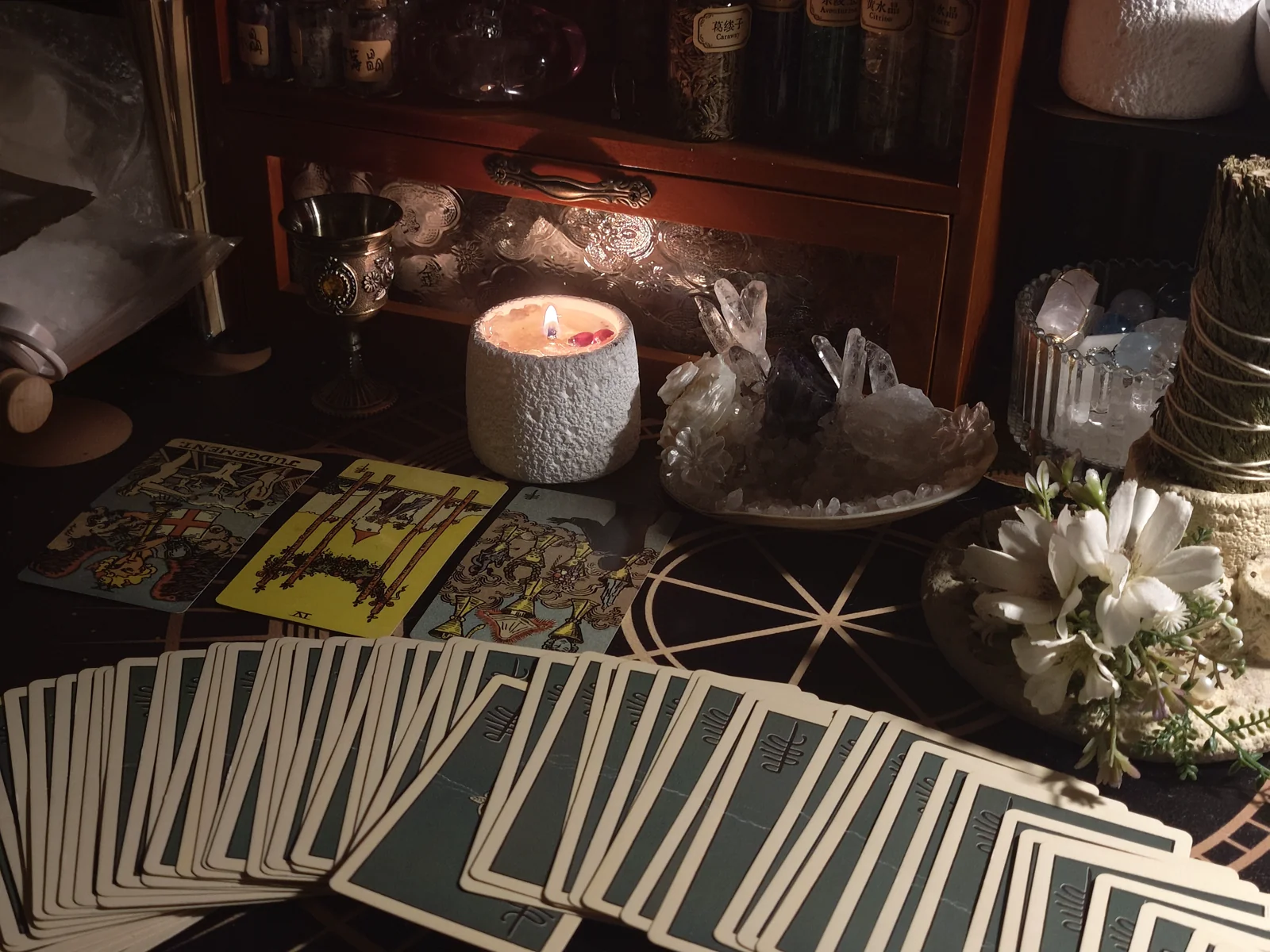 Tarot cards spread on a candlelit reading table with crystals, flowers and ritual objects